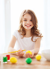 Image showing smiling little girl coloring eggs for easter