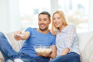 Image showing smiling couple with popcorn watching movie at home