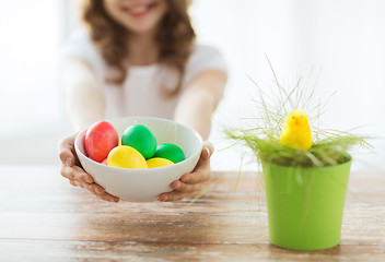 Image showing close up of girl holding bowl with colored eggs