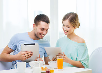 Image showing smiling couple with tablet pc reading news