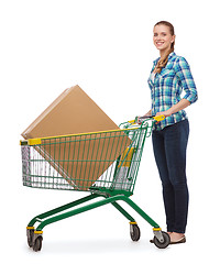 Image showing smiling young woman with shopping cart and big box