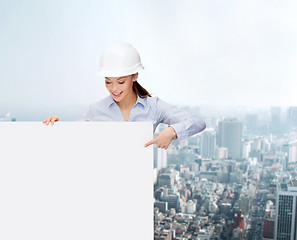 Image showing businesswoman in helmet pointing finger to board