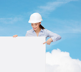 Image showing businesswoman in helmet pointing finger to board