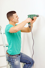 Image showing man with electric drill making hole in wall