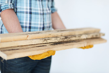 Image showing close up of male in gloves carrying wooden boards