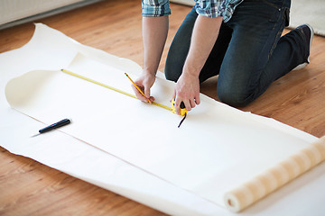 Image showing close up of male hands measuring wallpaper