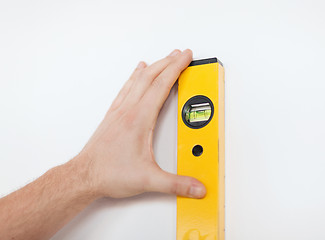 Image showing close up of male with spirit level mesuring wall