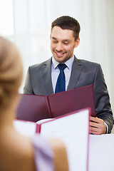 Image showing smiling young man looking at menu at restaurant