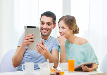 Image showing smiling couple with tablet pc reading news