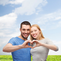 Image showing smiling couple showing heart with hands