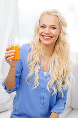 Image showing smiling woman with glass of orange juice at home