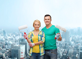 Image showing smiling couple in gloves with paint rollers