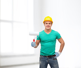 Image showing smiling manual worker in helmet with paint roller