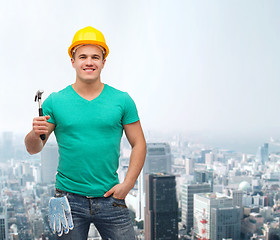 Image showing smiling manual worker in helmet with hammer