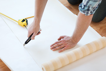 Image showing close up of male hands cutting wallpaper