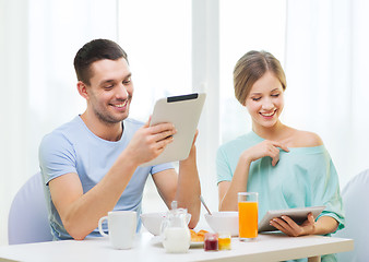 Image showing smiling couple with tablet pc reading news