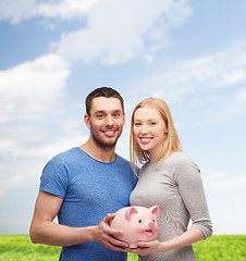 Image showing smiling couple holding big piggy bank