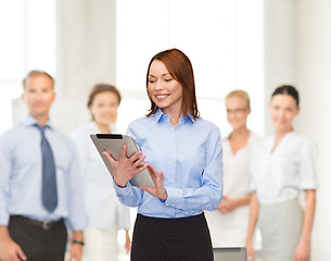 Image showing smiling woman looking at tablet pc at office