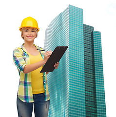 Image showing smiling woman in helmet with clipboard