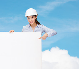 Image showing businesswoman in helmet pointing finger to board