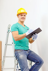 Image showing smiling man in protective helmet with clipboard