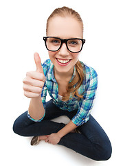 Image showing smiling woman in eyeglasses and showing thumbs up