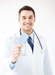 Image showing young male doctor with pack of pills