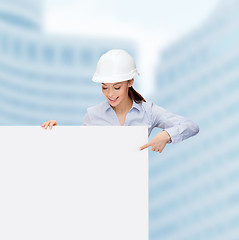 Image showing businesswoman in helmet pointing finger to board