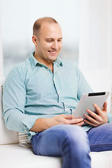 Image showing smiling man working with tablet pc at home