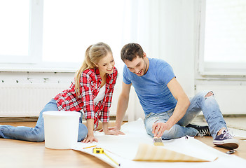 Image showing smiling couple smearing wallpaper with glue