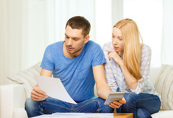 Image showing busy couple with papers and calculator at home