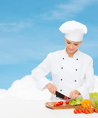 Image showing smiling female chef chopping vagetables