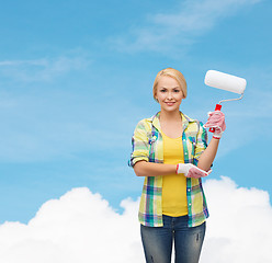 Image showing smiling woman in gloves with paint roller