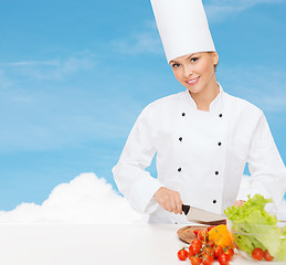 Image showing smiling female chef chopping vagetables