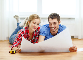 Image showing smiling couple looking at blueprint at home