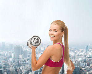 Image showing smiling woman with heavy steel dumbbell