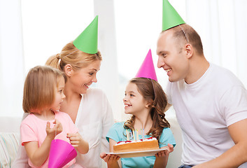 Image showing smiling family with two kids in hats with cake