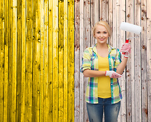 Image showing smiling woman in gloves with paint roller