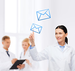 Image showing smiling female doctor pointing to envelope