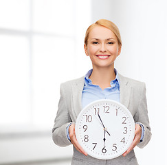 Image showing smiling businesswoman with wall clock