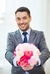 Image showing smiling handsome man giving bouquet of flowers