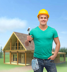 Image showing smiling manual worker in helmet with hammer