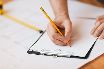 Image showing close up of male hands writing in clipboard