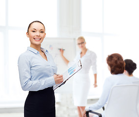 Image showing young smiling businesswoman with clipboard and pen