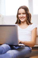 Image showing smiling teenage girl with laptop computer at home