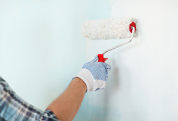 Image showing close up of male in gloves painting wall