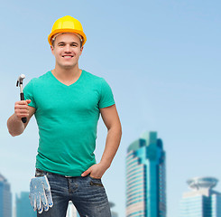 Image showing smiling manual worker in helmet with hammer