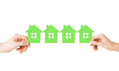 Image showing man and woman hands with many green paper houses