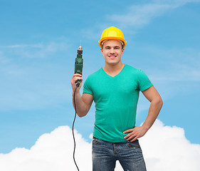 Image showing smiling manual worker in helmet with drill machine