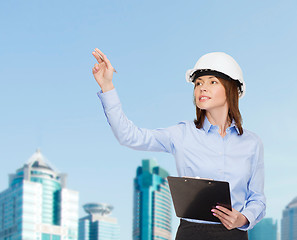 Image showing smiling businesswoman in helmet with clipboard